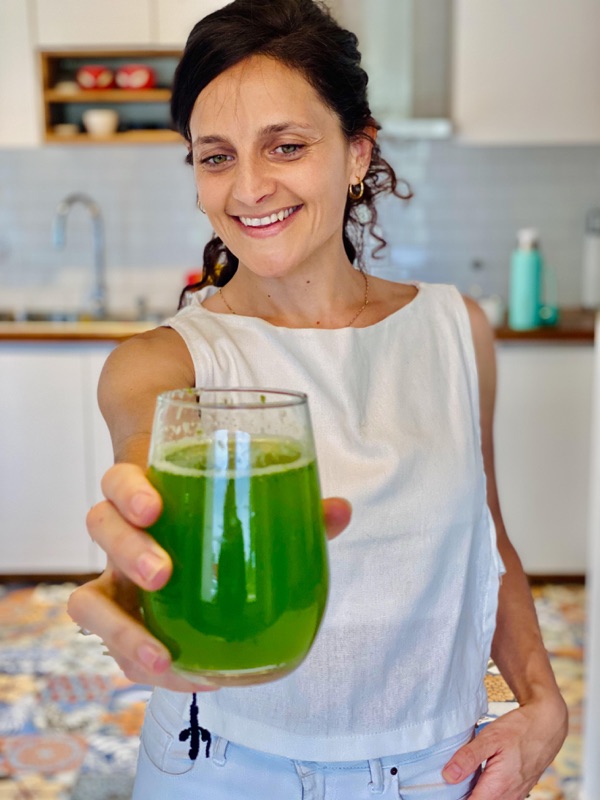 Juli ofreciendo un vaso de jugo verde hacia la cámara